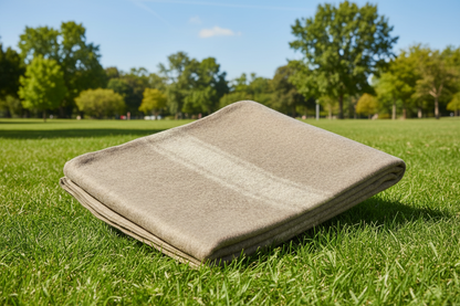 Beige blanket on grass with trees in the background